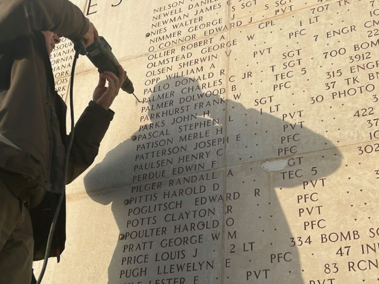 A mason drills a hole to add a rosette next to the name of Tech Sgt. Charles C. Palmer Jr. on the Walls of the Missing at Luxembourg American Cemetery. (ABMC photo)