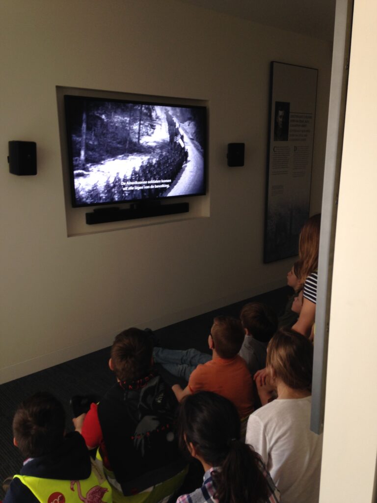 Students watch "Flanders Field: Remembering Their Sacrifice" in the renovated visitor center at Flanders Field American Cemetery.