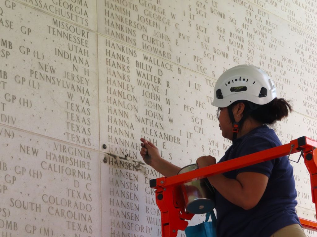 Julie Hilaga, an interpretive guide at Manila American Cemetery, places the rosette Jan. 18 next to the name of Pfc. David C. Hansen.