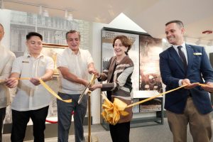 Four people cut a gold ribbon in front of the art exhibit to kick off events for the commemoration of the 80th anniversary of the liberation of Manila.