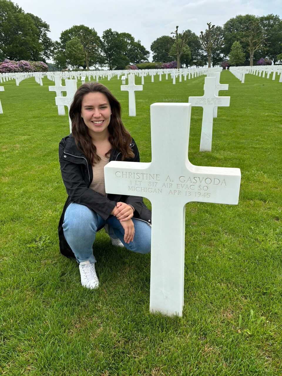 U.S. Air Force ROTC cadet and ABMC International Fellow Catherine Prince poses next to the headstone of 1st Lt. Christine A. Gasvoda. While learning more about the service members buried at the site, Prince learned one of the four women buried there was a native of a town near her home. Credits: American Battle Monuments Commission.