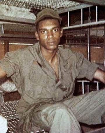 Specialist Fourth Class Larry Alonza Graham in uniform sitting on a bunk bed.