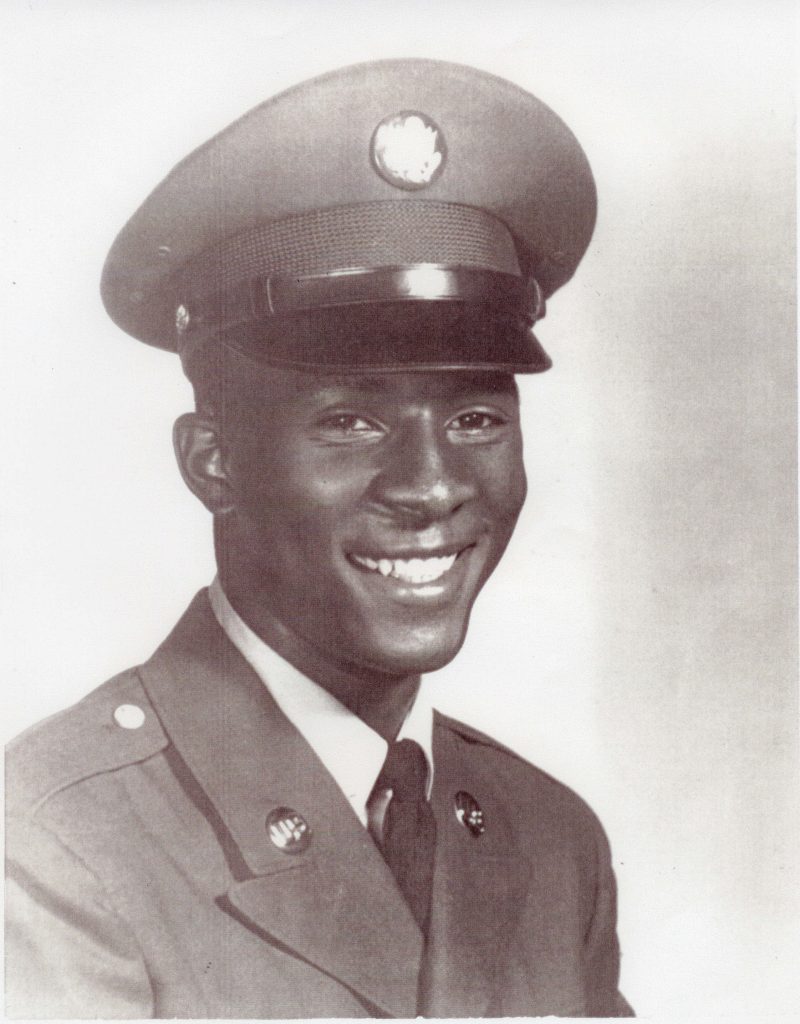 Portrait of a smiling young man wearing a formal military uniform and cap.