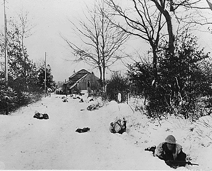 Troops of the United States 7th Armored Division advance along a road towards St. Vith in Belgium, retaken in the final liquidation of the Battle of the Belgian Bulge. Credit: National Archives. 